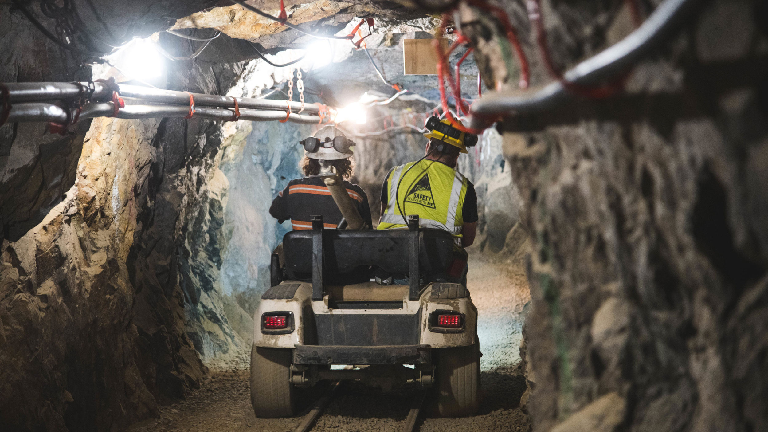 two engineers driving a cart through a mining tunnel