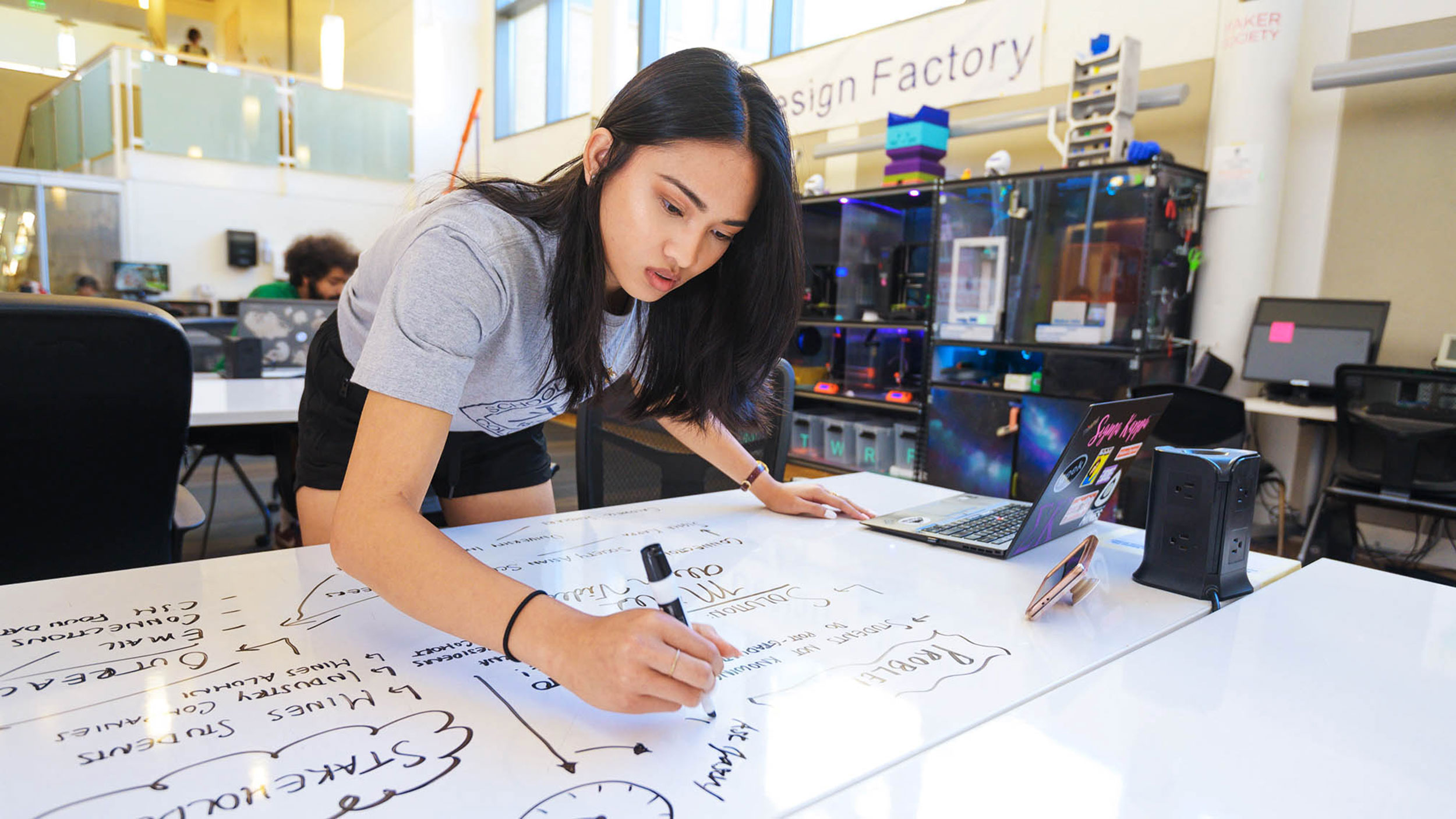 Female writing project outlines and requirements on a white board