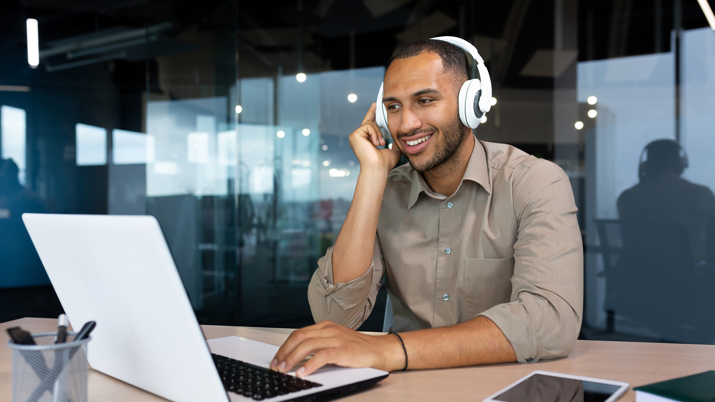 Man with headphones listening to man audio podcasts at work.