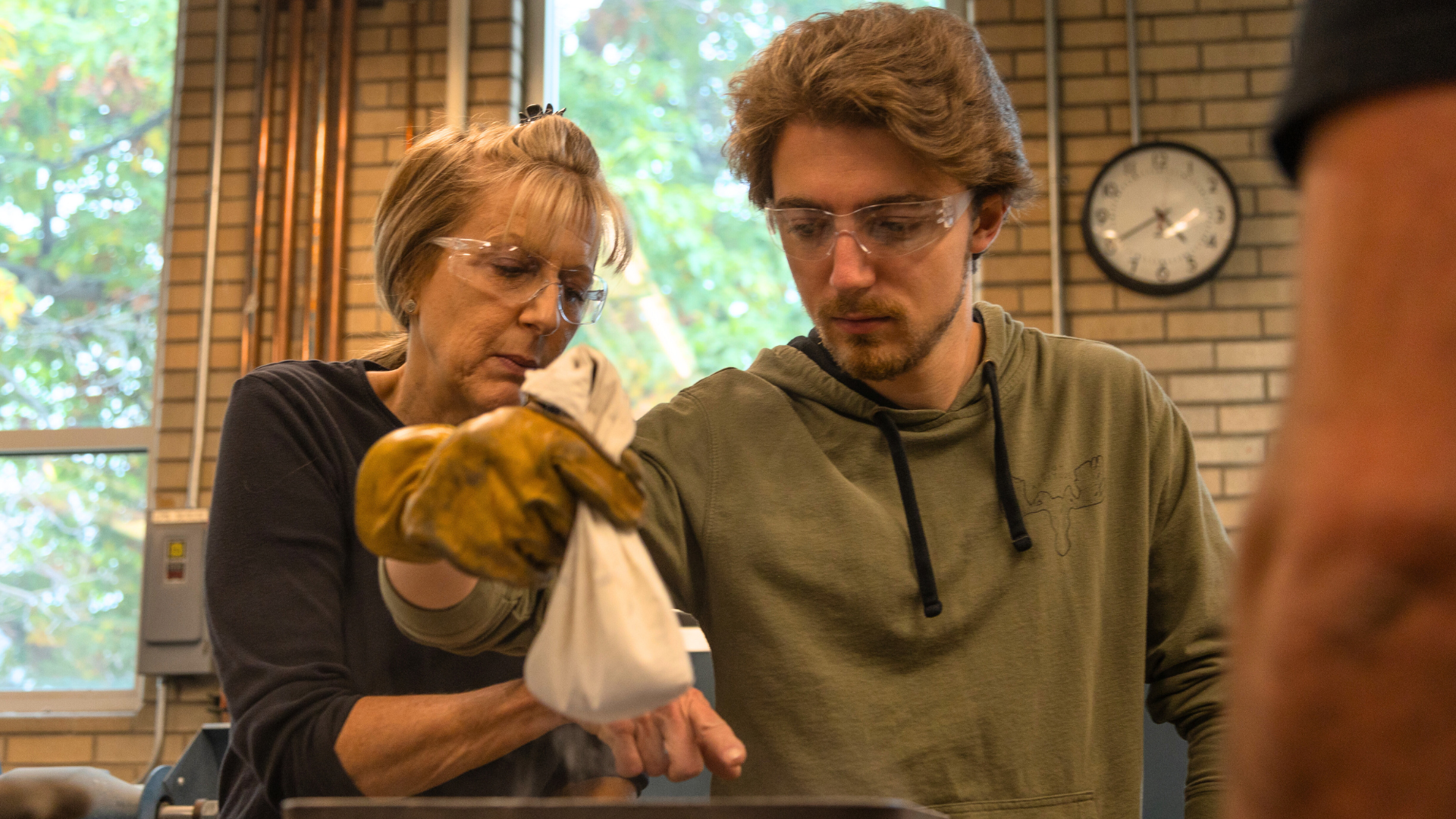 A student and their parent prepare their glass in the Mines Hot Shop